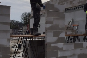 De kloostertuin woningen krijgen meer vorm door het opgaande metselwerk! Na het leggen van de betonplaten voor de vloer is het nu tijd om met betonblokken de eerste muren op te zetten.